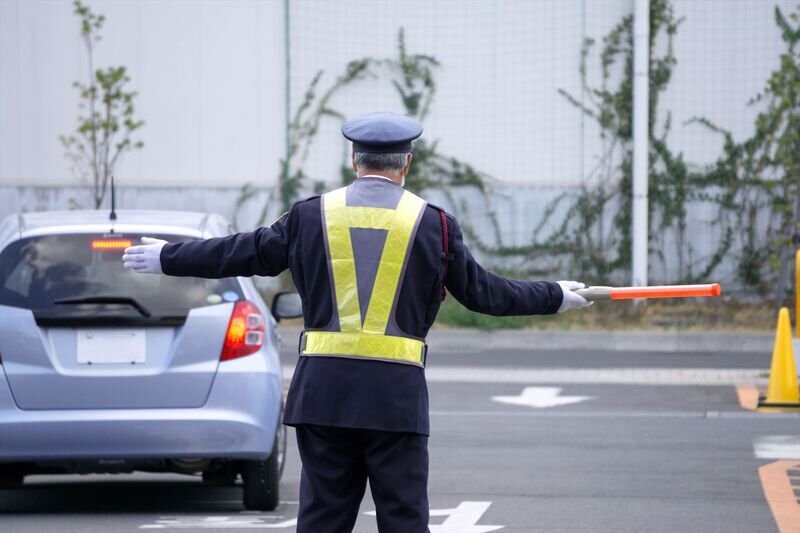 駐車場で交通誘導する警備員